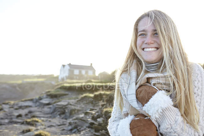 Glückliche junge Frau, die sich am Strand in Schal hüllt, Konstantinbucht, Kornwand, Großbritannien — Stockfoto