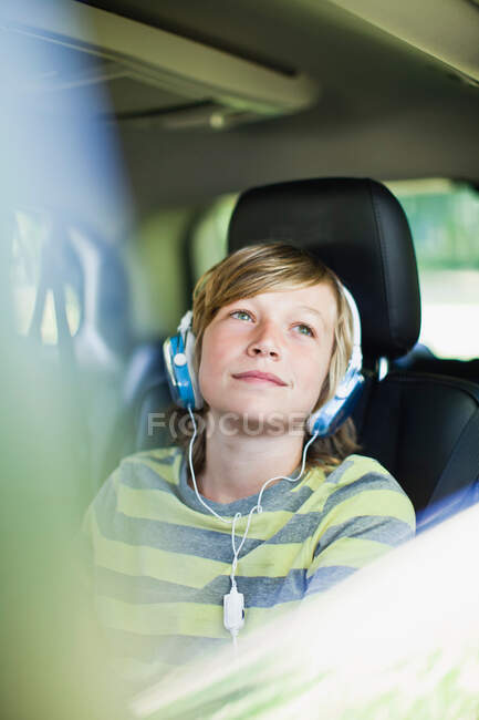 Garçon écoute écouteurs dans la voiture — Photo de stock