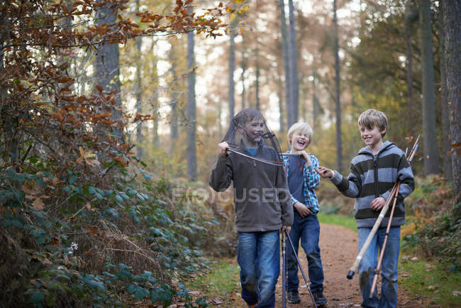 Niños caminando en el bosque con equipo de pesca - foto de stock