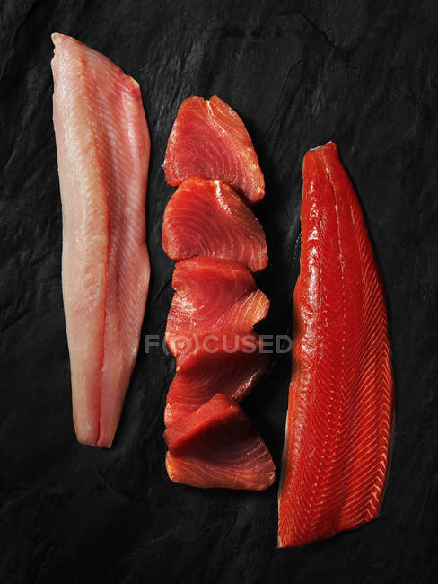Raw fish fillets on dark wood, top view — Stock Photo