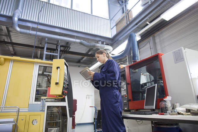 Женщина инженер мониторинга завода машины с помощью цифрового планшета — стоковое фото