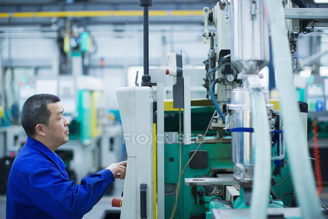 Worker at small parts manufacturing factory in China, pressing button on control panel — Stock Photo