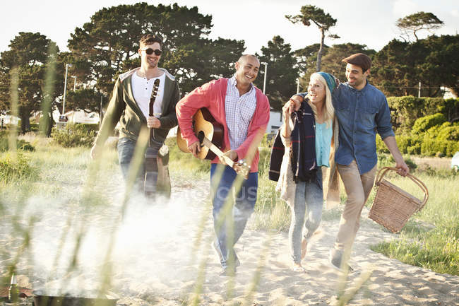 Vier Freunde mit Akustikgitarre und Picknickkorb am Strand, dorset, uk — Stockfoto
