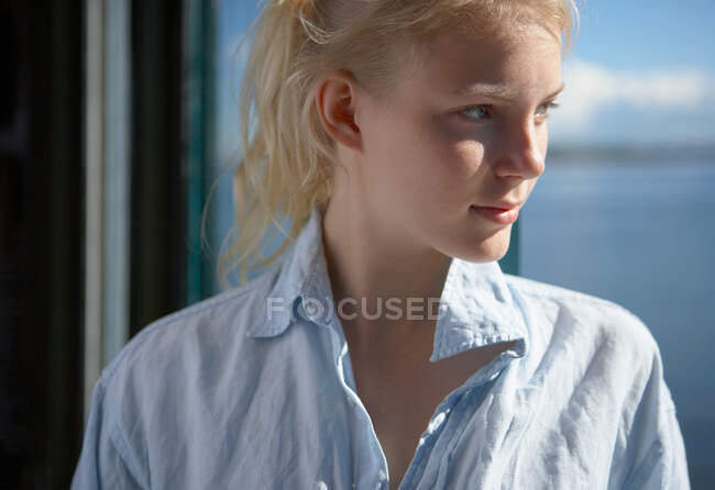 Jovem mulher por janelas de casa de praia — Fotografia de Stock
