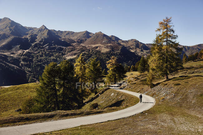 Ciclista su strada con montagne in lontananza, Vallese, Svizzera — Foto stock