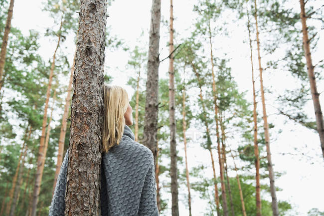 Mid adult woman leaning against tree, low angle — Stock Photo