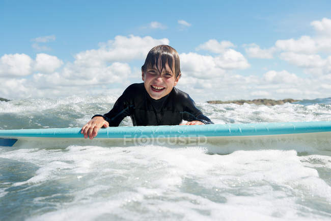 Niño en tabla de surf en el mar - foto de stock
