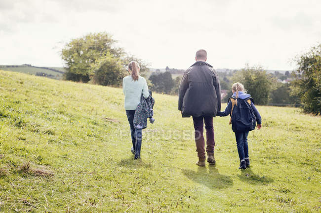Padre e hijas caminando en el campo - foto de stock