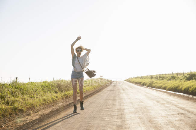 Mulher adulta média andando na estrada do país, acenando braços no ar — Fotografia de Stock