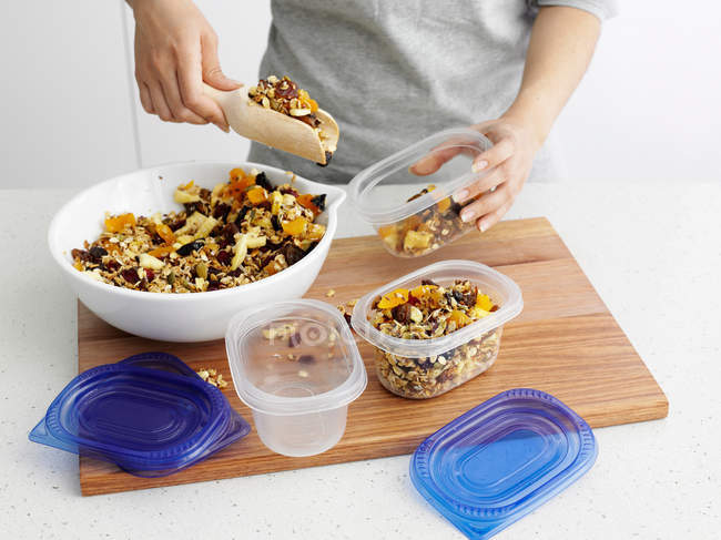 Cropped image of woman putting granola into containers — Stock Photo