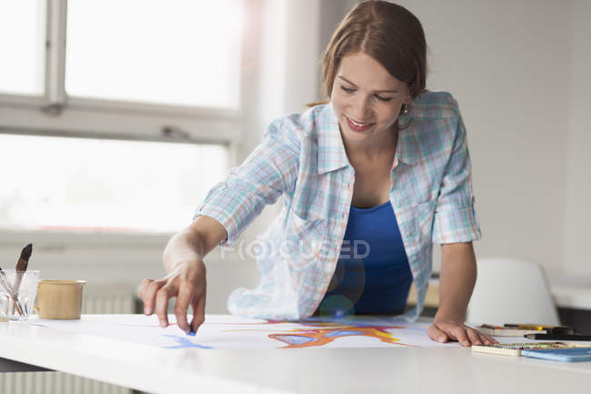 Jovem artista feminina desenhando por mesa dentro de casa — Fotografia de Stock