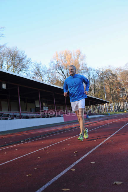 Mature man running on sports track — Stock Photo