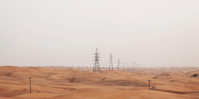 Pilones eléctricos en el desierto, Dubai, Emiratos Árabes Unidos - foto de stock