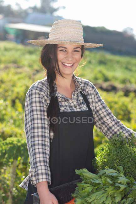 Mujer joven con verduras cultivadas en la granja - foto de stock