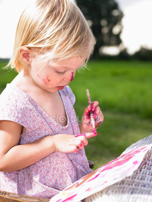 Маленькая девочка рисует на зеленом поле — стоковое фото
