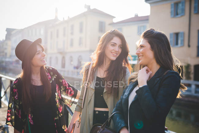 Três mulheres jovens conversando na orla do canal — Fotografia de Stock
