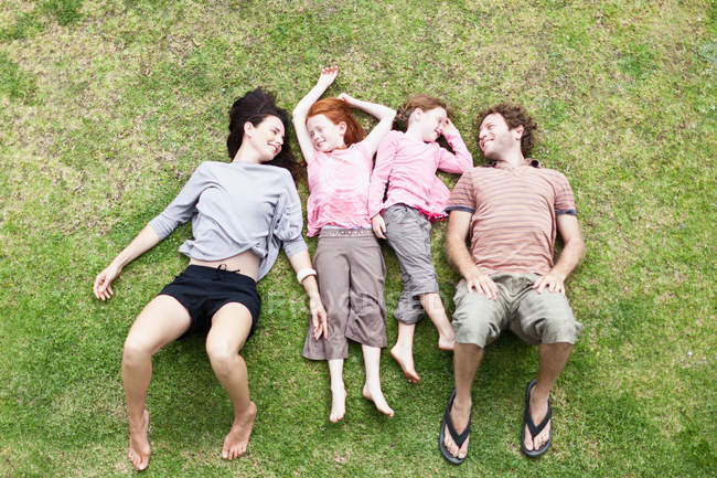 Семья, лежащая в траве вместе — стоковое фото