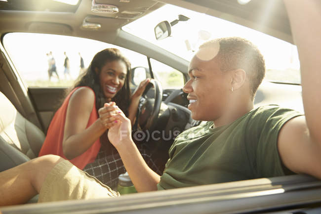 Молода пара сидить в машині тримаючи руки — стокове фото