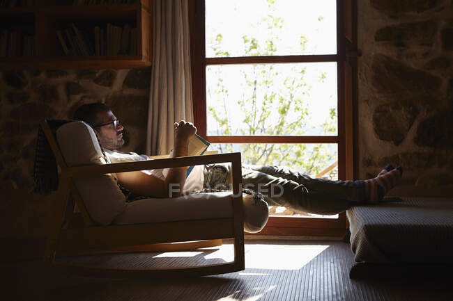 Metà uomo adulto lettura libro mentre si rilassa in salotto — Foto stock
