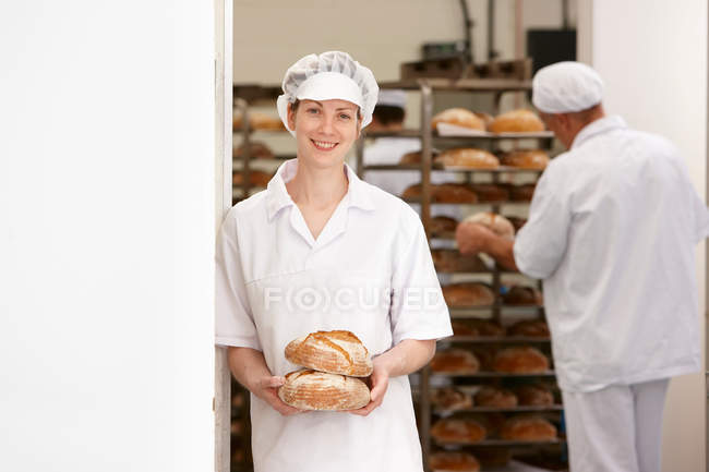 Chef sosteniendo panes en la cocina - foto de stock