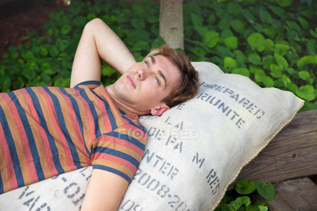 Jeune homme couché sur un sac rêvant — Photo de stock