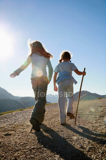Vue arrière de la randonnée des filles sur la montagne au coucher du soleil — Photo de stock