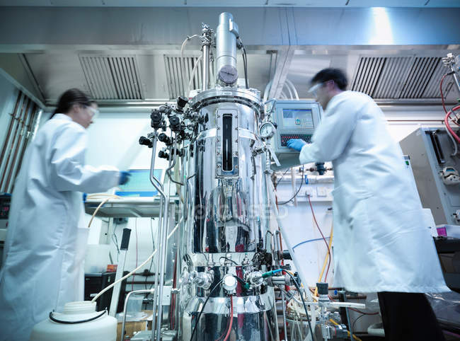 Ученые, работающие в производстве белков, где клетки и образцы культуры создаются в биореакторе — стоковое фото