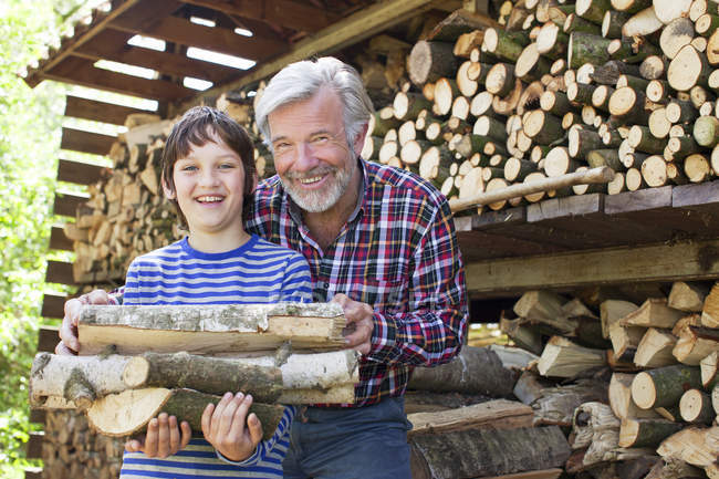 Abuelo y nieto con troncos - foto de stock