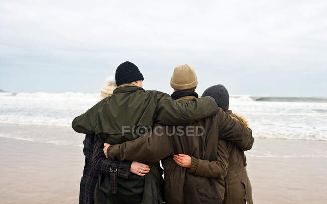 Gruppo di amici che si abbracciano sulla spiaggia — Foto stock