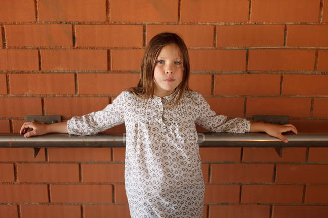 Mädchen lehnt an Geländer an Ziegelmauer — Stockfoto