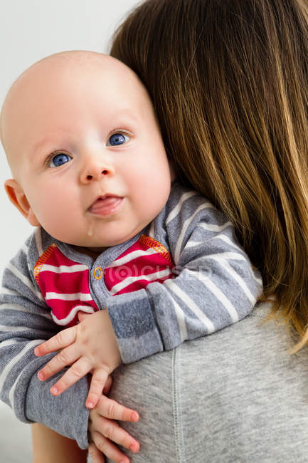 Mother holding baby son over shoulder — Stock Photo