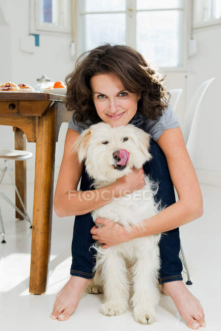 Woman hugging dog in kitchen — Stock Photo