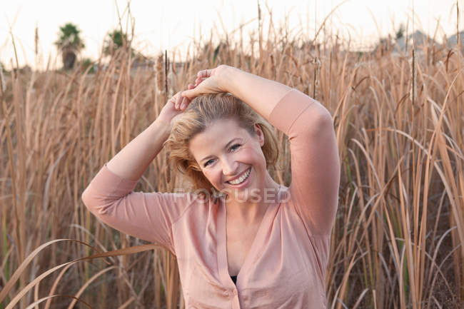 Mulher sorridente em pé no campo de trigo — Fotografia de Stock