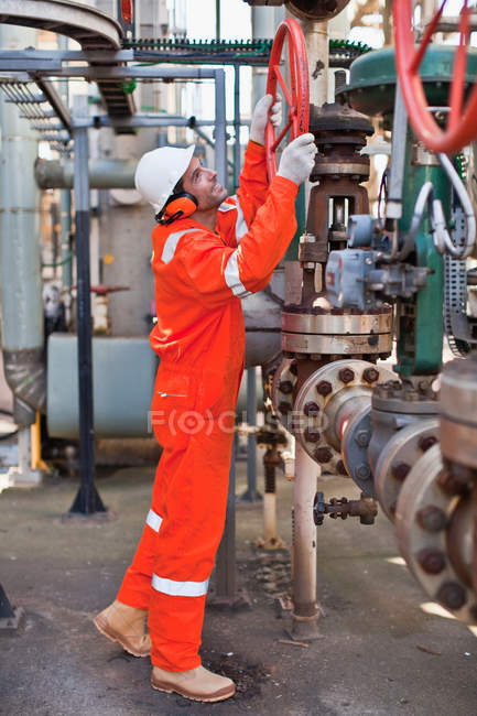 Worker adjusting gauge at oil refinery — Stock Photo