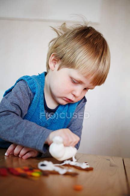 Мальчик украшает пряничное печенье — стоковое фото
