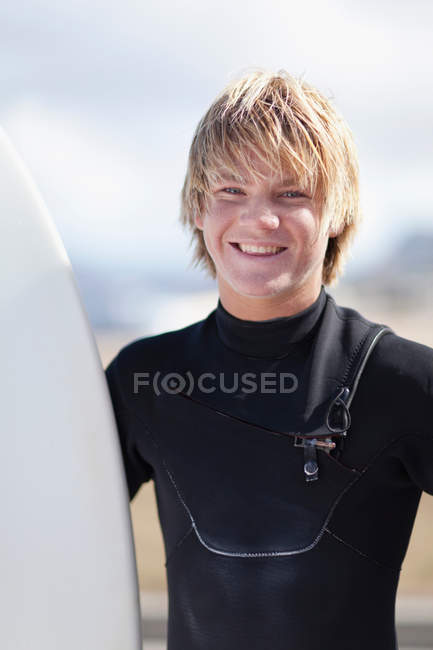 Teenage surfer holding board en la playa - foto de stock