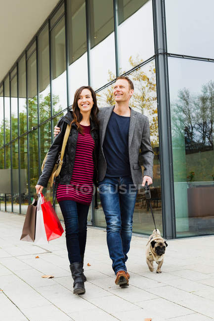 Couple walking dog on city street — Stock Photo