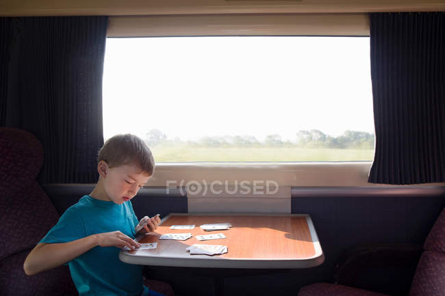 Giovane ragazzo con carte da gioco in treno — Foto stock