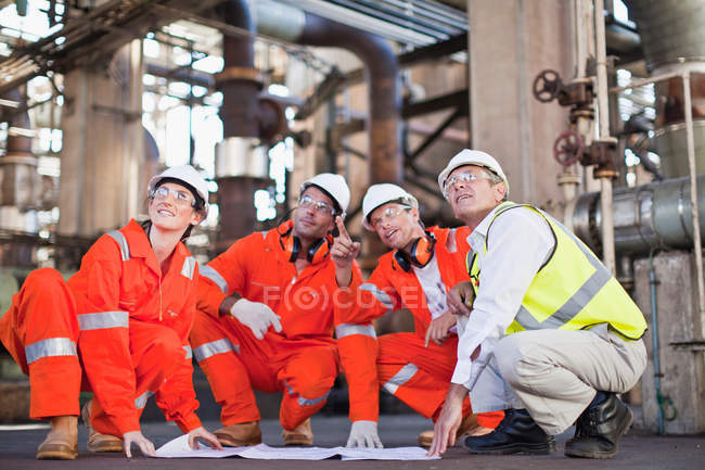 Travailleurs avec des plans à la raffinerie de pétrole — Photo de stock