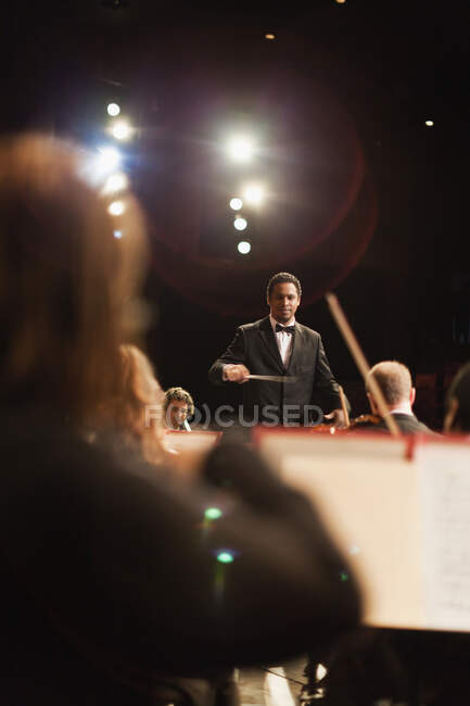 Director agitando bastón sobre orquesta - foto de stock