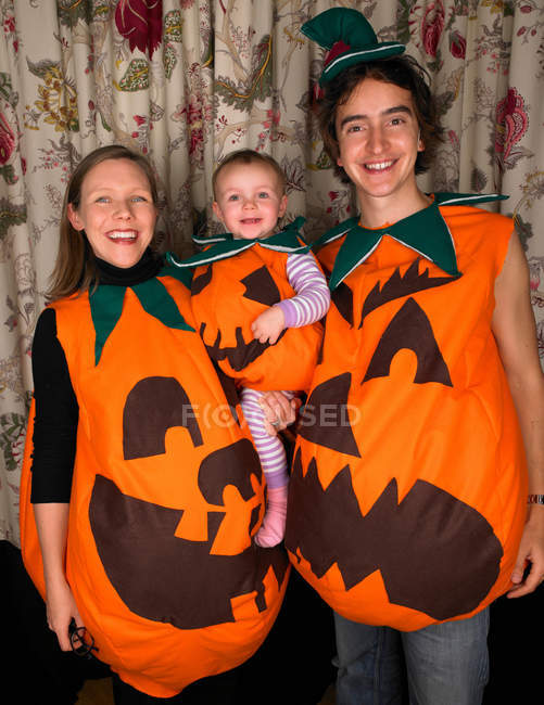 Портрет молодої щасливої сім'ї, одягненої як гарбузи для Хеллоуїна — стокове фото