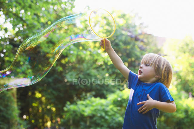 Menino fazendo bolha de grandes dimensões no quintal — Fotografia de Stock