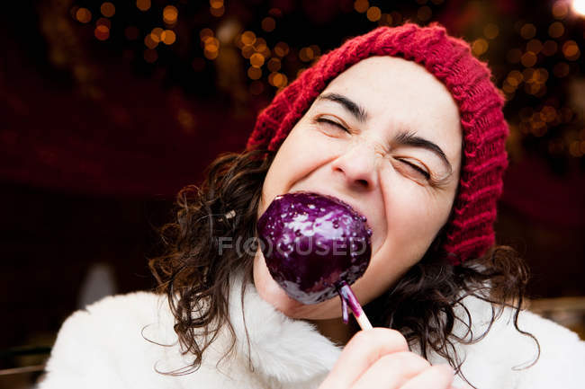 Frau beißt in kandierten Apfel — Stockfoto