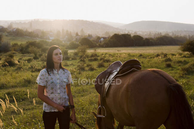 Mulher segurando cavalo no prado — Fotografia de Stock
