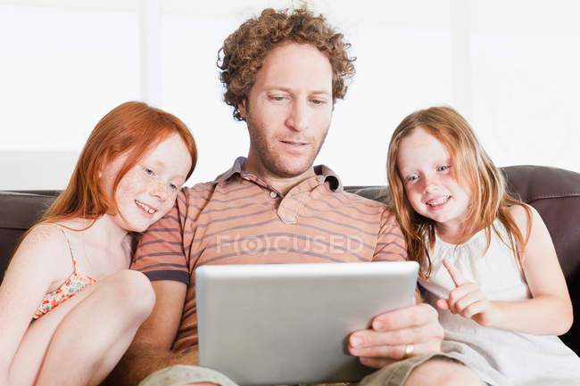 Отец и дочери используют планшет — стоковое фото