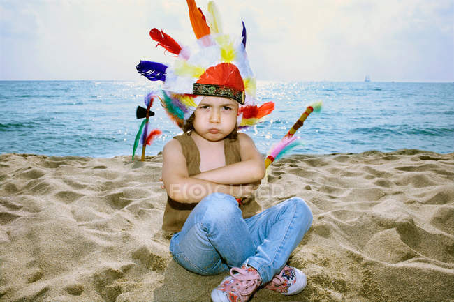 Toddler in Indian headdress on beach — Stock Photo