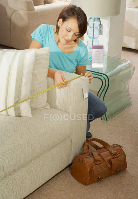 Woman measuring sofa in furniture store — Stock Photo