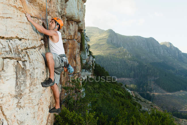 Climber scaling steep rock face — Stock Photo