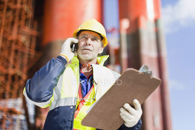 Worker talking on cell phone on oil rig — Stock Photo