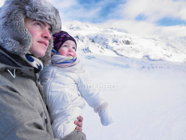 Батько тримає дитину в засніженому пейзажі — стокове фото